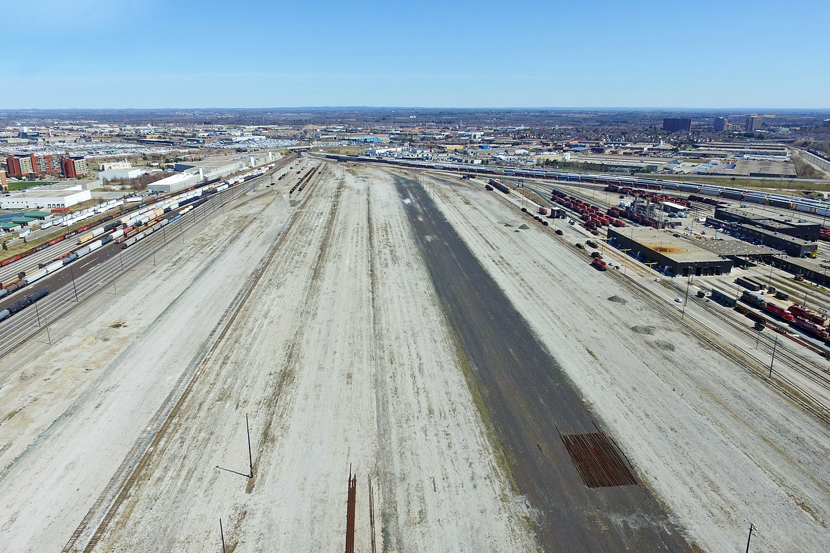 This was the first opportunity I'd take to fly over heavily restricted private property, and I almost got away with it. Except I found out I had actually driven onto CP property to fly it, and didn't even realize it! The maintenance worker was rather grumpy while informing me, but nonetheless allowed me to leave without the whole cop ordeal, which is good. While I did tell them I was flying a drone, I neglected to tell them I flying directly over their yard. Lol. Nonetheless, I gotta be more careful.

This was one of the shots I took, and probably the ugliest one I got, in terms of what is shown. These were the hump tracks at CP's Toronto yard, and under the wrath of Hunter Harrison, the hump yard here and at many other CP yards were shut down. The hump yard closed, I believe, in early 2013, and was ripped in its entirety the next year. While Hunter is largely to blame for massacring the yard, it's an important reminder that cuts are a major factor in the private sector world today, and CP is not the only railroad closing yards, ripping up lines and laying off employees. Outsourcing and economic recessions surely have not helped either.

The fate of this yard, besides the fact it is closed, is unknown. The north holding tracks could very well be shoved over towards the engine shops, and the rest of the land could be sold off for several millions of dollars. More optimistically, perhaps there is a brighter future ahead. Maybe one day, under a president less focused on stocks and more on railroading, this yard may exist again. However, the current ideology of class 1 railroads involve slow speeds, two to three mile long trains, and reclassifying of freight cars several times from origin to destination. Nonetheless, this makes it very hard to attract customers, and many have waved the rail industry goodbye because of this. 

That's probably enough ranting on my part. On the plus side, this vast area would make for a great rally race, and if the ground is solid enough, maybe a full on drag race. Just don't hit a pole or crash into the stacked rails. Take notice Hunter, you could make a lot of money off of this. Of course, the only way this would likely happen is illegally. Unlike some U.S (Oakvand foreign continent cities, illegal racing and sideshows are pretty rare here, even in Toronto's sketchy parts like this one. Lets keep it that way.