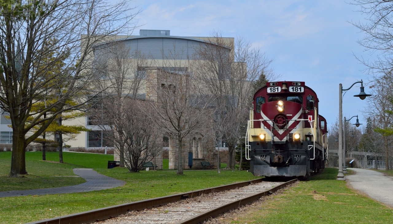 OSR's daily way freight rolls southbound through downtown Guelph with venerable MLW power, 12 cars, and the little yellow van.  At left we can see the River Run Center Theater and Concert Hall.  In front of the theater you will see an old stone wall.  This is the last remaining piece of the CPR Guelph freight shed.  The freight shed once stood where the theater currently sits, but was destroyed by fire in 1991.  (http://riverrun.ca/our-story/history/)  The remainder of the front wall was moved slightly south, where it still stands today.Note the railings leading out of frame from the path at right (the original CPR Goderich Sub main), they lead onto a small jetty built over the speed river.I got a shot of OSRX 8235, OSRX 1210 southbound from the jetty last August: http://www.railpictures.ca/?attachment_id=20394