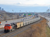 <b>Marker light lit on the rear of a long potash train</b> CN B730 with 152 loads of Potash destined for Saint John, NB is slowly starting to leave Turcot West in Montreal after changing crews. Power is a trio of ES44AC's, with CN 2934 & CN 2812 at the head end and CN 2940 bringing up the rear, with its marker light lit. At right is the skyline of downtown Montreal.