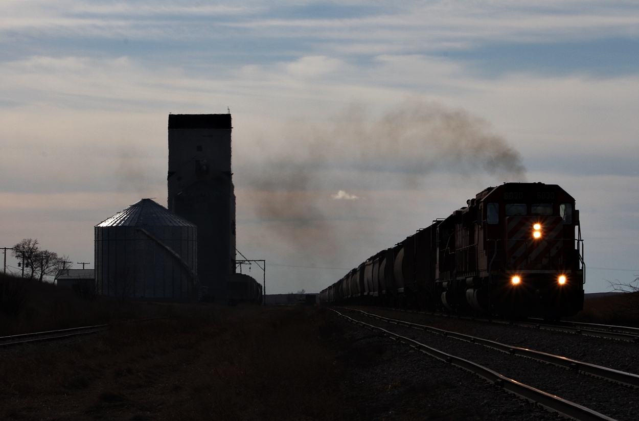 CP EMD's roar past the old grain elevator at Mossbank on its way north to Moose Jaw with 65 loads.