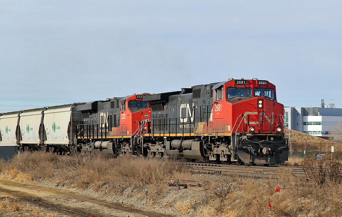 Dash 9-44CW CN 2681 and ES44DC CN 2323 head a train of Campotex empties east past Clover Bar.