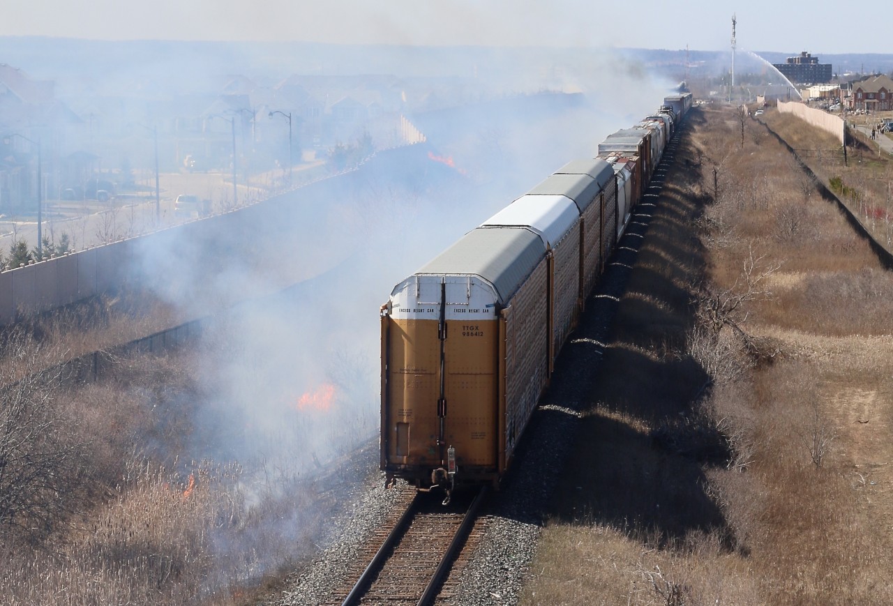 The passage of CN local 551caused numerous fires through Milton thanks to a sparking wheel set. CN 382 was lined on its block and chose to try to make it through town before the fires got worse. The train ended up fanning the flames covering much of the town in smoke, as the fire department tries to battle one of the larger fires in the distance.