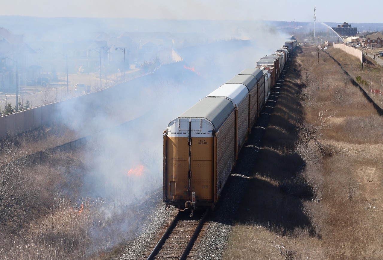 The passage of CN local 551caused numerous fires through Milton thanks to a sparking wheel set. CN 382 was lined on its block and chose to try to make it through town before the fires got worse. The train ended up fanning the flames covering much of the town in smoke, as the fire department tries to battle one of the larger fires in the distance.
