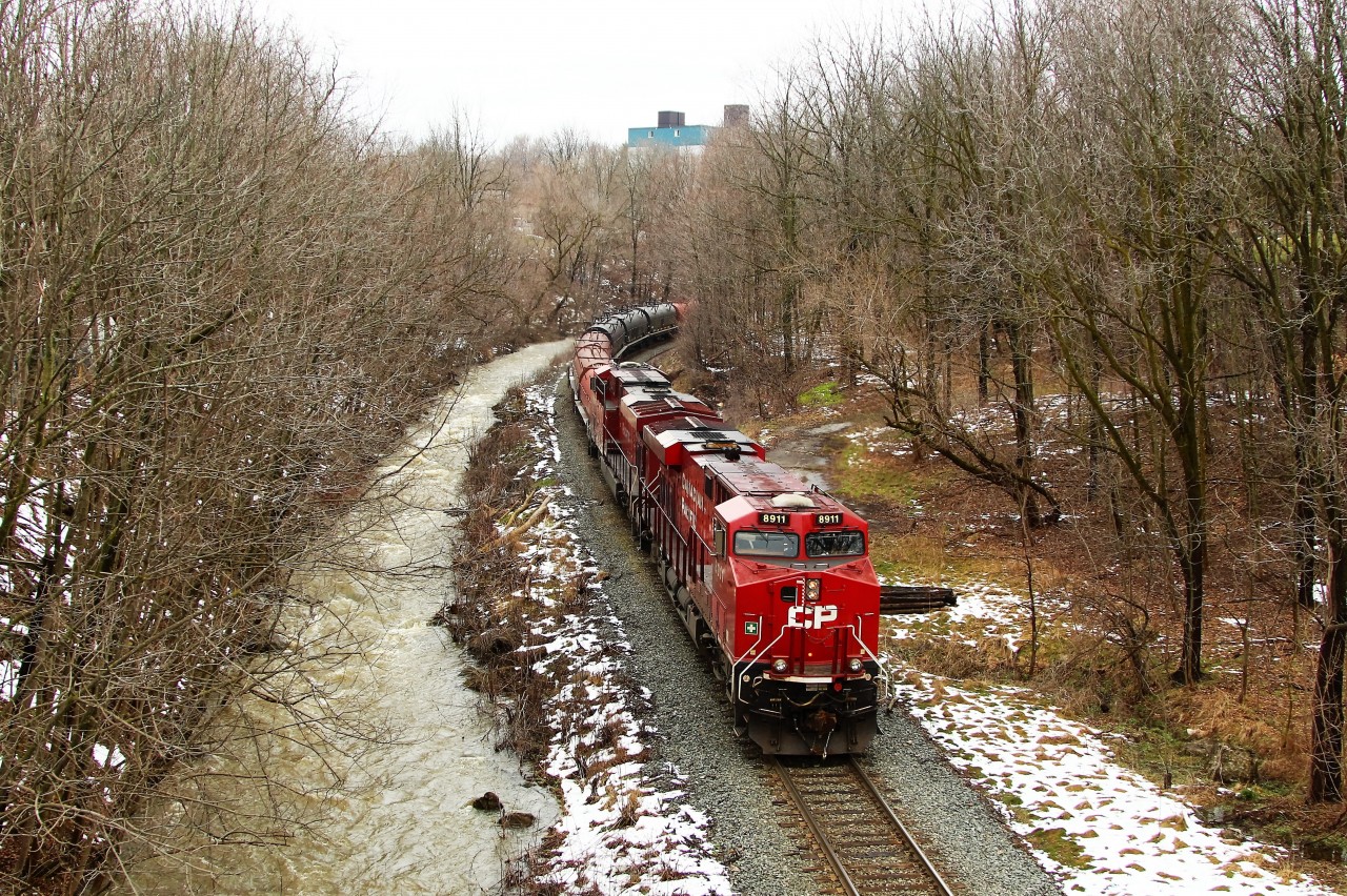 After having waited for several hours for CP 247 to clear the Hamilton sub because of slick rails, todays CP 246 is led by CP 8911 with CP 8895 along the rain swollen Grindstone Creek and are about to go under the Dundas Street (highway #5) overpass in Waterdown.