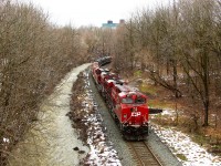 After having waited for several hours for CP 247 to clear the Hamilton sub because of slick rails, todays CP 246 is led by CP 8911 with CP 8895 along the rain swollen Grindstone Creek and are about to go under the Dundas Street (highway #5) overpass in Waterdown.