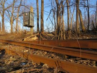 Cast aside. Spring is a good time to see things before the leaves come out and the weeds get tall. The crossing equipment box dates from the CN days when trains did not stop before crossing Innisfil Street. While it is no longer in use, the rail in the foreground is from Carnegie dated 1900. This is the oldest rail I have seen in the Barrie area.