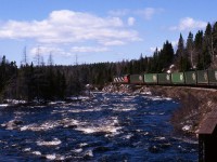 DOWNGRADE AT KITTY'S BROOK - As photographed from the vestibule of Coach 757, Terra Transport Mixed Extra 935 West with single unit NF210 935 has just crossed the first of two bridges over that brook overflowing with spring run-off on April 20, 1987. This view gives some perspective of the grades encountered on the former Newfoundland Railway during the photographer's first of five runs on the Bishops Falls to Corner Brook mixed service. By now the railway was pretty much fully containerized but living on borrowed time. 
