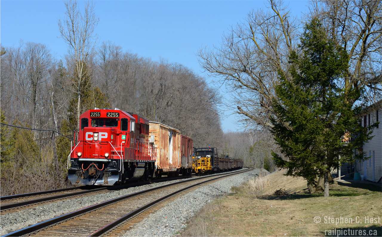 An interesting sight, a new ECO leading an old rail train, filled with 40 and 50 year old modified Gondolas, camp cars... and a MOW caboose at the tail end in the picturesque town of Campbellville Ontario. 
Operationally, this was interesting - anyone care to shed light to why? The purpose of this run was to drop on on the Hamilton sub, happened as follows
a) Run entire consist into the north track at Guelph Junction
b) 254 takes the Hamilton sub ahead of the rail train
c) 2255 detaches from train, enters OCS under work authority, reverses back into CTC to take the Hamilton sub to wye, re-enters CTC at Guelph Junction 'east'
d) Finishes weing, re-attach to rear of rail train on north track
e) Shove train clear of the CTC into OCS, to take the south track then Hamilton sub connector, rounding the curve at 3 MPH
f)dropping rail between Guelph Junction and Waterdown once clear of the wye track.
Thanks for any and all comments from those in the know. I did not follow, went home due to commitments.