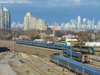 The Toronto skyline is lit up in the brilliant late winter sun and stainless steel of VIA's classic Canadian equipment reflects the blue skies above.<br><br>
Vancouver-Toronto #2 arrived a few hours earlier, spent time at the fuelling racks, set off the dining and park cars before parking the remainder of the train in the yard as seen waiting for their turn for maintenance and cleaning. <br>
#1 is also preparing for an 8 PM departure, with the park car in the foreground and the rest of the train including a pair of locomotives behind me. #1 will reverse from TMC to Union Station to board passengers and depart for Vancouver. Other than the change of location and lack of CP F's on the point of this train, the look of this train is simply classic, ride or shoot it while you can folks!



