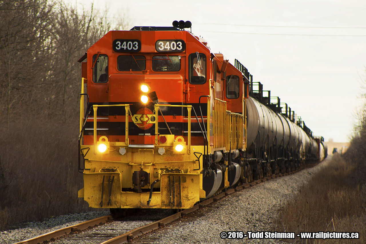 Prior to this photo, I had made many attempts at photographing this train in it's daily activities...either switching at Imperial Oil facility, or trying to capture it as it trundles up the line to the Garnet yard. However, either poor lighting, extreme weather conditions, or just not enough time all proved to be the barriers that prevented me from getting a good shot.

It was my first attempt when on a cold and blustery day after Easter, I chased the train as it departed Esso, and went up a few concessions where I stood at the railway crossing and waited...and waited...and still waited. At this pint, standing at the crossing near open fields and feeling the windchill of that afternoon, I came up with a nickname for the Southern Ontario Railway - just like they used to do in the golden days. I christened it "Slow but Operational" on this 1.75 mile stretch to the Garnet yard.

All things considered, my timing was perfect this day as I finally saw SOR 3404 in the lead with 3403 behind it pulling a string of tanker cars from the Imperial Oil facility to the Garnet yard.