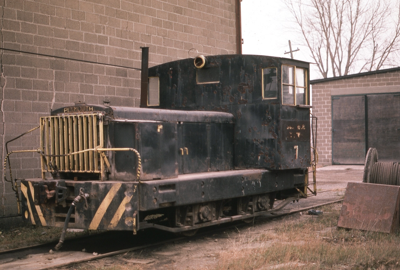 Here's a somewhat rare shot of the old Canada Crushed Stone Ltd all-purpose locomotive that sat up on the CCSL property at Dundas for a few years after the operation shut down in the early 1970s. The structures of the CCSL were prominent features along the hillside over Dundas for many years, and for a time the outfit interchanged with the CN and the TH&B which came up thru Dundas by way of Aberdeen yard. I do not know where this unit ever ended up, I would imagine it was trucked out as the quarry "mainline" had been torn up by the time I took this photo. Using information supplied by noted author and authority on Industrial and "Critter" locomotives, Steve M. Timko, this 24 Tonner Plymouth was built in 7/7/1927 model" HLC-3, a 127 HP gas-mechanical Climax R6u engine. It had been on the CCSL since 1930. (Hope I got that right, SMT !!) The quarry is still in business, now ships via truck and the main operation faces Hwy 5 near Brock Rd.