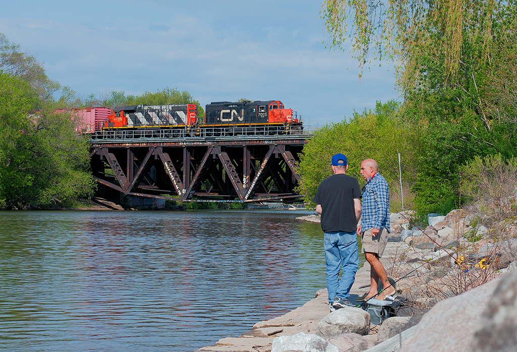 Two local fisherman go on about their morning as CN 556 trundles east with cars for Distribution, Metro and Lantic Sugar.