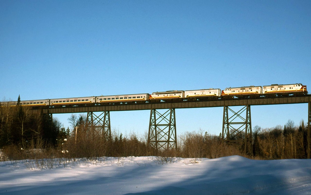 The northbound Snow train crosses Bellevue trestle early on the morning of January 14, 1998. 1751, 1753, 1761 and 1768 head for Agawa Canyon with 18 cars. The 1761 had just been released for service a week prior after receiving some work and new paint and it glows in the low winter sun.