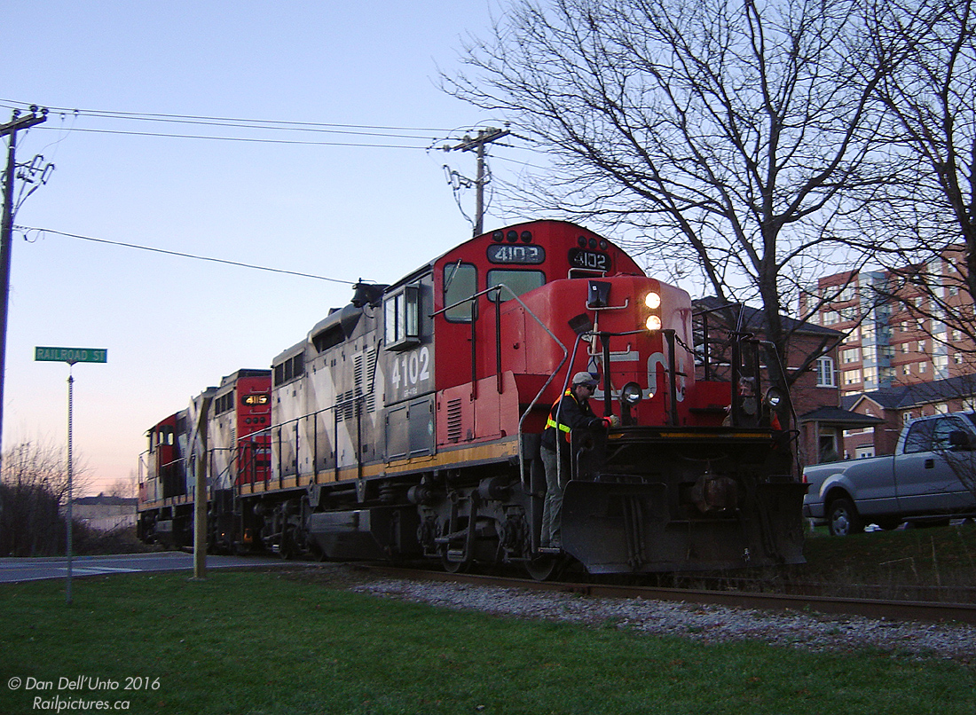 The CN RTC is juggling trains left and right on the CN Halton Sub, just before the evening rush hour GO trains start swarming his territory. He (or she) has managed to squeeze through GEXR #431 on its way back home, a CN #392, and this rare evening move right in the middle of the evening rush hour: what was probably CN #559 clogging up the south main track to work the Dixie Cup Spur in downtown Brampton.  CN GP9RM's 4102 and 4115 have dumped their 3-car train on the south mainline, and the crew are riding the front steps as the two Geeps head down the Dixie Cup Spur across Railroad St. by Haggart to lift a pair of boxcars from the Georgia Pacific plant at Queen & McMurchy (originally opened as the Dixie Cup Company). They'll then head back to the main, couple to their train, and back down again with the inbound cars to spot. After finishing up, they'll back homeward against the "GO rush", fighting for time to run the Brampton East-Peel single track gauntlet. Two or so years later the switch to the mainline was taken out, G-P switched to trucks, and the RTC never had to worry about having to squeeze a #559 through downtown during rush hours.