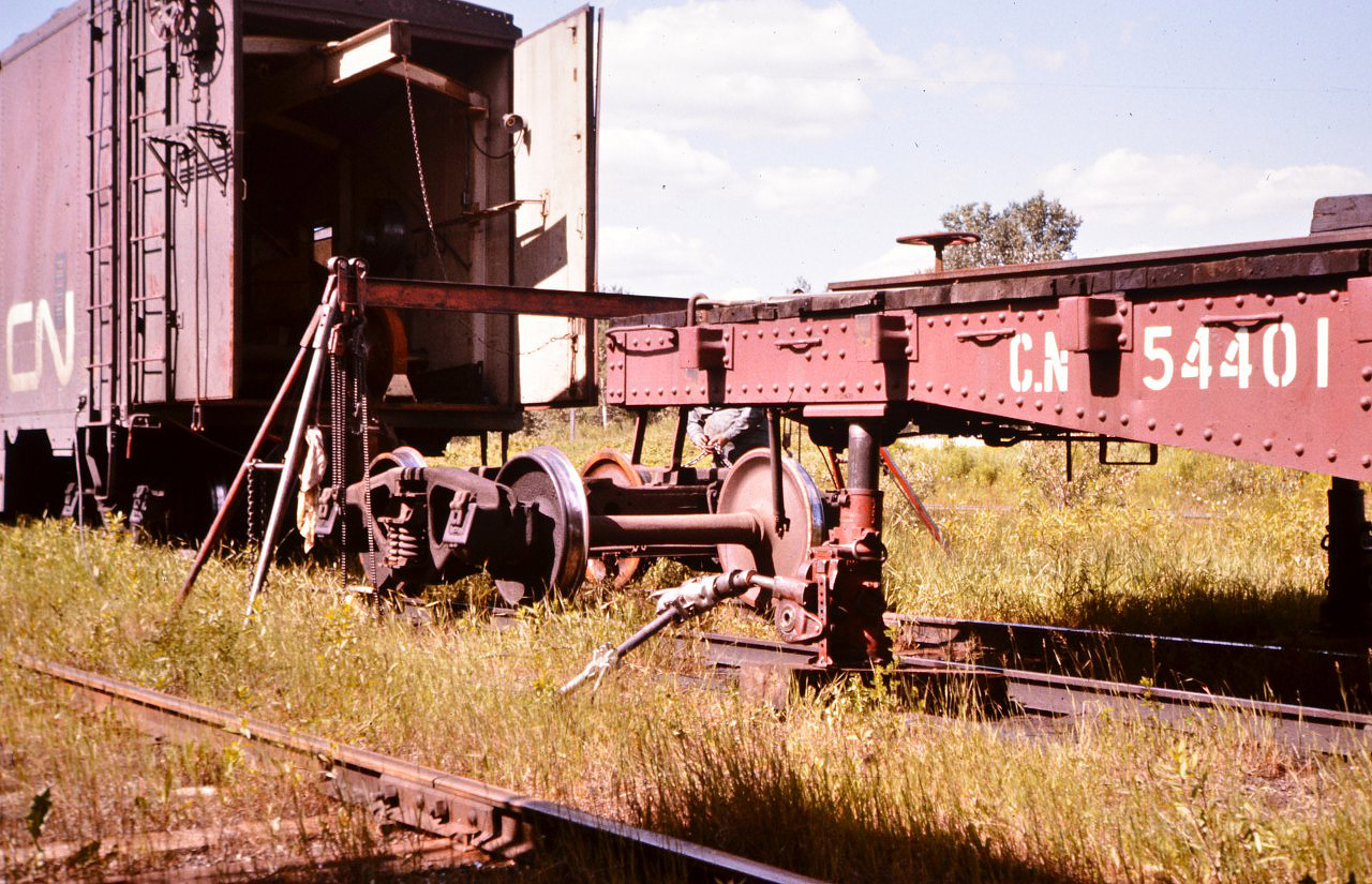 The working end of a CN road repair car offers up an idea of how labour intensive a field wheelset change out was 40 years ago. CN 54401 (work equipment machinery flat) gets a new set of wheels at Oba, ON in the summer of 1976. These 'shops on wheels' came with all the tools and equipment needed to make emergency road repairs, and when completed, the guys would retire to the accommodation portion of the car to cook, eat and sleep.