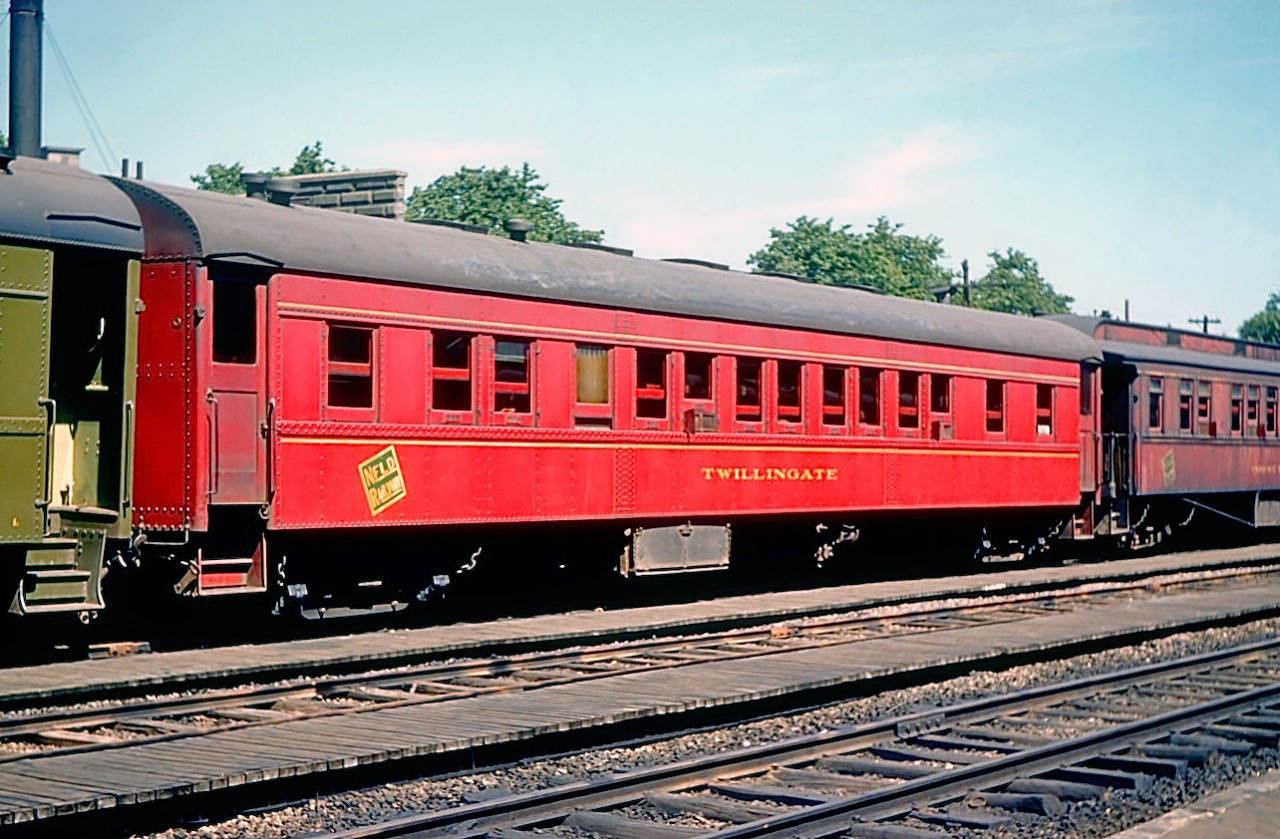 Former Newfoundland Railway sleeping car "Twillingate" is seen at St. John's, Newfoundland on July 29, 1952.   It continued to carry NR colours until 1955 at which time it was repainted in CN livery.  Built in 1938 by National Steel Car, it was of all-steel construction, and was fitted out with 8 sections and 1 drawing room.  Converted to work service in 1970 (as CN 5011), it was retired and moved to Corner Brook where it joined the Railway Society of Newfoundland museum at Humbermouth station. For many years it bore the name "Humber" but in 1999 its original name was restored.   

In retrospect, I wish now that I had also paid attention to the elderly coach to the right wearing faded NR paint.

[Note: geotagged location not exact]