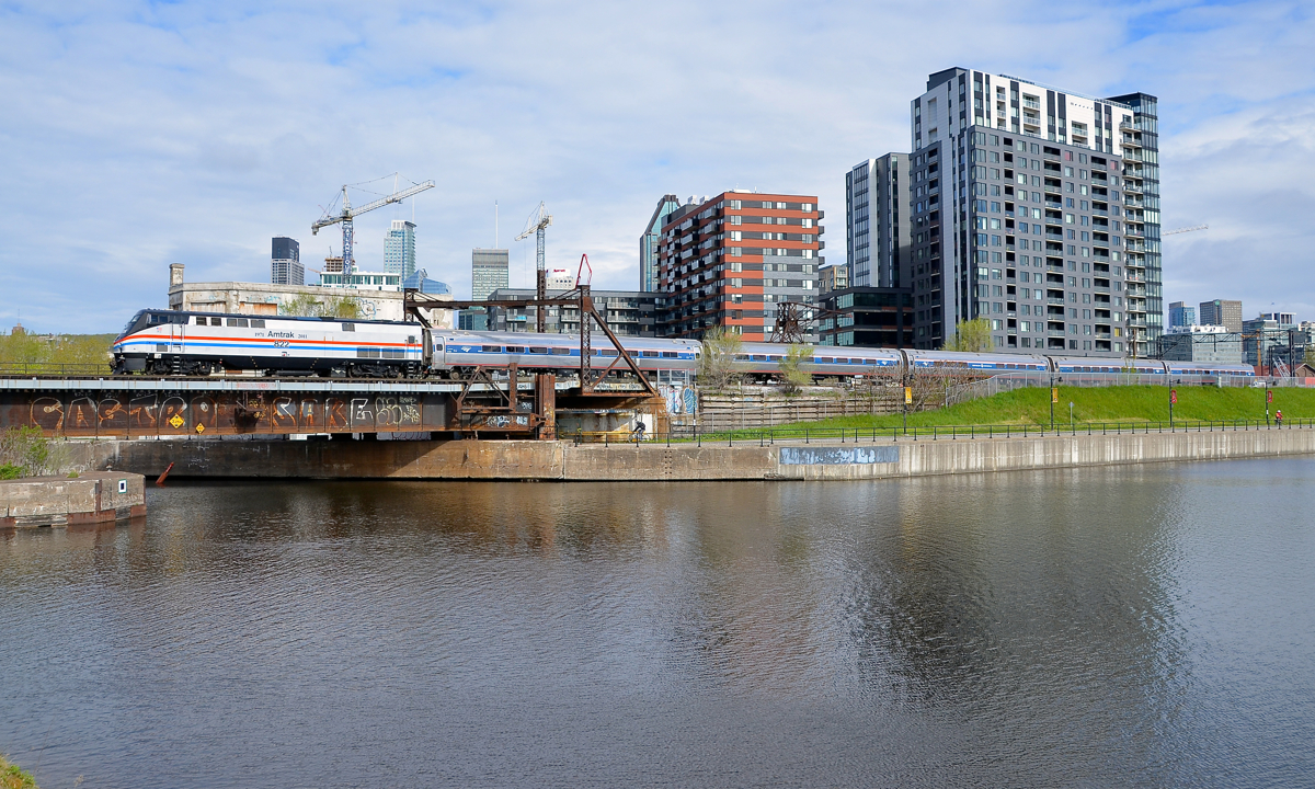 Non-stop Amktrak heritage units in Montreal. For about the 6th time in 2 weeks, an Amtrak heritage unit is seen leading the Adirondack. Both AMTK 184 and AMTK 822 (the latter seen here pushing the Adirondack towards Central Station in Montreal) have visited Montreal very often recently. Behind the train is Montreal's ever changing skyline, with a number of cranes prominent behind Wellington Tower.