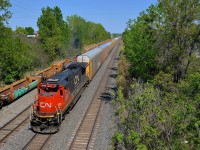 <b>A solo C40-8 past stored well cars.</b> A shorter than usual CN 401 is powered by just a single C40-8 (CN 2039) as it passes stored well cars on CN's Montreal sub near the entrance to Taschereau Yard.