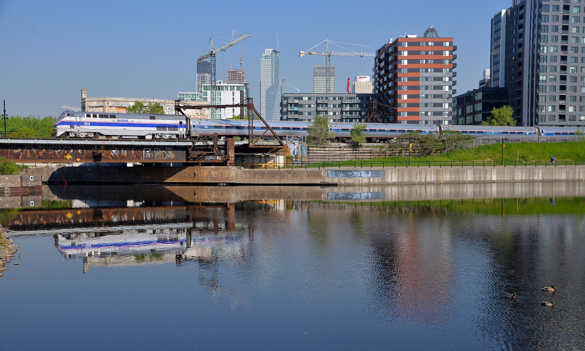 A phase IV unit reflected. Phase IV heritage unit AMTK 184 is reflected in the mostly still waters of the Peel Basin as it pushes the deadheading Adirondack towards Montreal's Central Station. This is about the fifth or 6th time this unit has been to Montreal in the month of May.