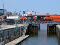 <b>A pair of GP9's over an open lock in the Port of Montreal.</b> A local transfer job is leaving the Port of Montreal with a decent sized train consisting of about 30-40 cars and GP9's CN 7272 & CN 7204 for power. It is passing an open lock at the eastern end of the Lachine canal; this lock is only used for pleasure craft. In the background is a much larger ship, namely the <i>Venture</i>, which has been docked here for about a month now.