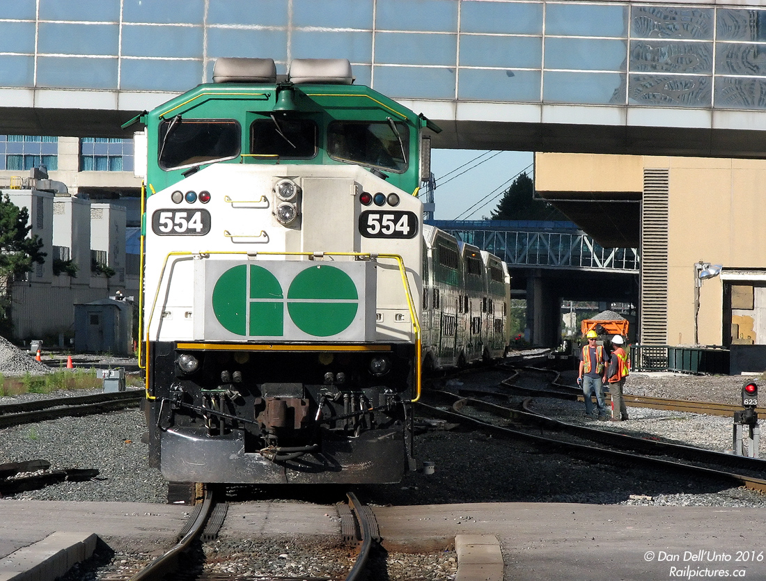 After arriving seven minutes earlier from Oshawa, GO Transit train #909 departs Toronto's Union Station westbound at 9:43am on time, making all stops to Aldershot. Trailing F59PH 554 has popped out into the sunlight from the confines of the train shed, and is passing by two Toronto Terminals Railway (TTR) employees doing maintenance work in the Union Station Rail Corridor.