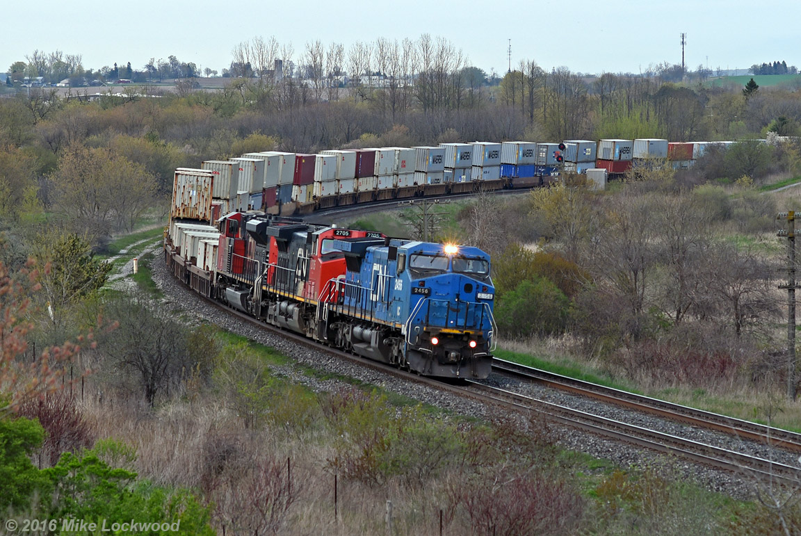 IC 2456, IC 2705, and CN 8851 lead 149's train through the broad curve at Bowmanville. Traces of the one time town spur to the Goodyear plant are slowly succumbing to vegetation or the wrecking crew, the only visible evidence in this view being the path to the left of the train. The shot here is getting tighter and tighter, and unless some foam hero does a little covert trimming, this classic view will be lost. 1914hrs.