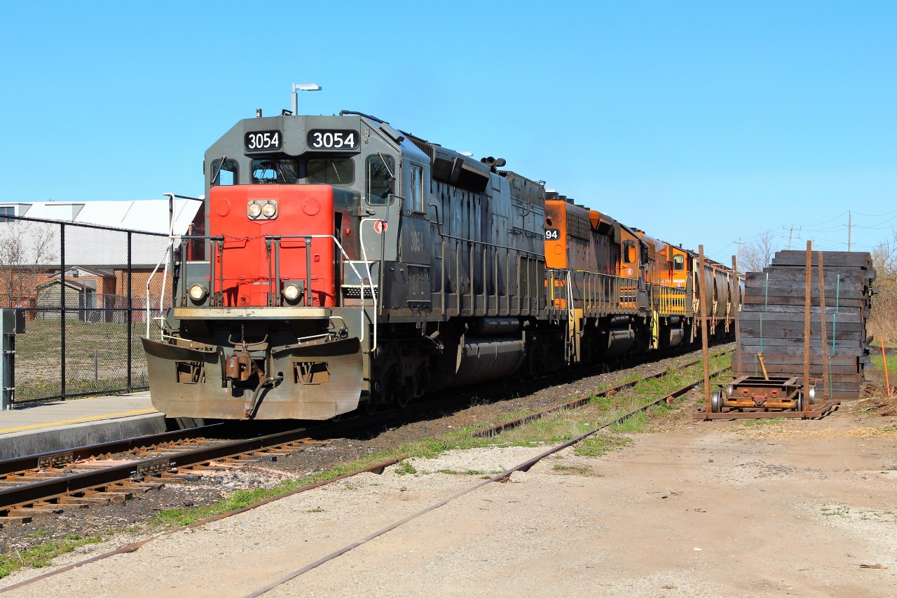 GEXR 3054 leads GEXR 3394 and GEXR 3030 past the Acton Go station and up to MM 35.48 at the Eastern Avenue crossing on their way to Silver. At the right is a very large row of brand new ties with what appears to be  a tie pull cart in the front.