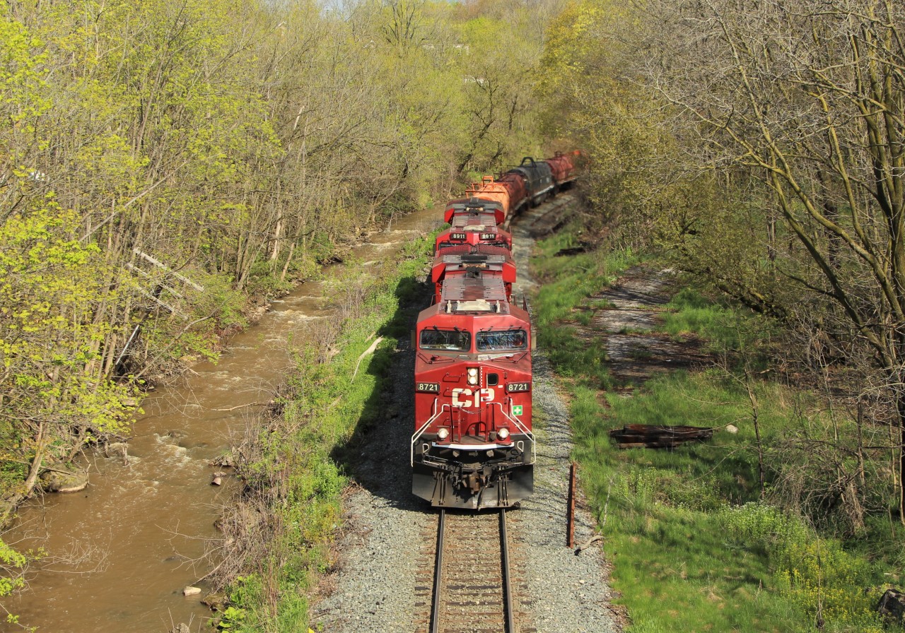 CP 246 rumbles down the hill with CP 8721 on point with CP 8911 for assistance as they pass beside the muddy Grindstone Creek and prepare to go under the Highway 5 bridge in Waterdown on their way to Desjardins.