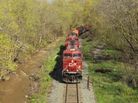 CP 246 rumbles down the hill with CP 8721 on point with CP 8911 for assistance as they pass beside the muddy Grindstone Creek and prepare to go under the Highway 5 bridge in Waterdown on their way to Desjardins.