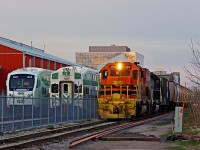 It took me long enough to get some GEXR pictures, but it finally happened. GEXR 431 had arrived from Mac Yard around 5pm at Kitchener Yard. The crew ran out of hours and tied down, and the relief crew arrived at around 6:30pm, having the train ready to shortly afterwards. However, since GO now owns the line as far as Park Street in Kitchener (where I'm standing), 518 (the train’s new number) was forced to wait for both GO trains and Via 87. Due to the enormous amount of construction going on at King Street for the new LRT, the GO yard switch was relocated to the west end of the yard. This means GO trains now have to pull up a few car lengths past Strange Street, and back in. Nonetheless, GO trains will soon be able to use the new much larger yard east of Kitchener station, making this scene no longer possible. In case you are wondering why there is a ridiculous light reflection on the building in the distance, ask Google, as they designed the windows that way.  <br><br> After holding for over an hour, GEXR 518 is finally on the way to Stratford with a string of empty salt hoppers for docks at Goderich. Tunnel motor 3054 is trailing (unfortunately not leading). Not sure where the rumours stand on 3054 leaving, however, it is still pumping it out for now. 