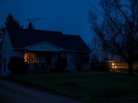 Twenty minutes after sunset, Canadian Pacific's Chicago to Montreal stack train no. 142 is seen passing by a farm house on a gloomy spring evening in Flamborough, Ontario. 

Having biked to this location from my house (about a quarter mile down the road) I managed to beat the train with less than a minute to spare. This didn't leave me with enough time to set up a tripod but with a frenetic guess at my exposure and steady hands I was able to save the shot.