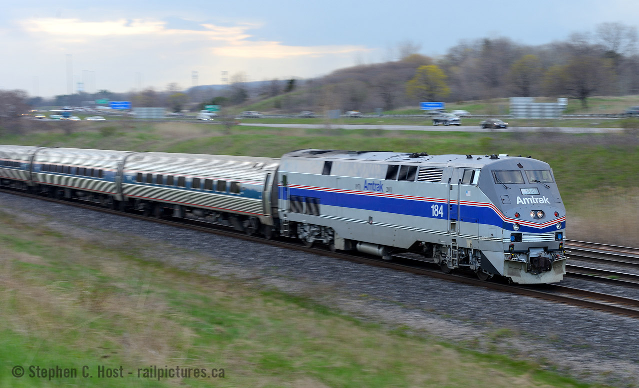 Zooming by the 403, VIA 98 is wasting no time to get to Aldershot for a station stop. Photo notes: 

When the light isn't in your favour.... make something with it - I'm shooting at a spot that would be backlit in the mid to late afternoon, the clouds are non existent behind me (thus too bright to shoot facing south with such a bright sky) and the clouds to the north west made for a perfect way to mash everything into the histogram of my camera's sensor. I opted to pan this shot given the light at hand being somewhat low, easier to force my camera to a low shutter speed.