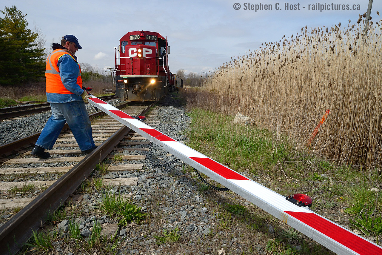 Railway crossing? During my OSR trip on April 30th (see my four previous photos) I took a detour to Zorra to shoot T69 who I heard switching the former St. Marys sub over the radio. While there, a farmer towing his tractor in a pickup truck ripped the gate off at Zorra, so the pictured Conductor had to move it to the side for the approaching westbound as well as for itself. The gate was simply off its hinge, and still flashing while lying on the track.
A rule 103 was quickly put in place and unfortunately for the crew and the RTC, I did not get the license plate of the offending farmer despite photographing the ordeal and a signal maintainer would have to come out to fix the crossing.