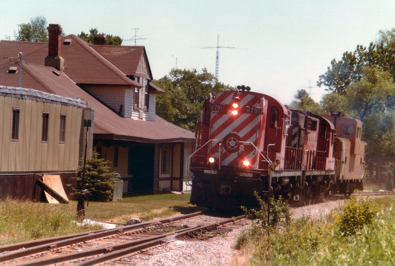 On a sweltering hot July day, I decided to hike in to an area I considered 'off-limits' by walking on the opposite side of the tracks from said property (Barnes). There was a southbound train that was going to stop on the siding for a brake test back in there.  Before I got to where I was heading, along comes a northbound 'caboose hop', I guess you could call it, heading for Guelph Jct. I heard him blowing for Parkside Dr crossing, and ran back; catching him just about to pass the old Waterdown North station. No chance at all to get cute with the shot, this was as good as it gets. Leader 8791 with CP 8737, a pair of MLW RS-18s, built back in 1958 and 1957 respectively. The station is still there, renovated for an office, I suspect.