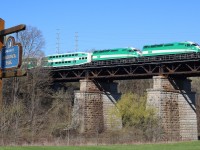 A double headed Eastbound GO train slows for Oakville station as it crosses high above Hogs Back park. The 16 Mile Creek runs between the two piers while Cross Ave is situated out of view to the right.