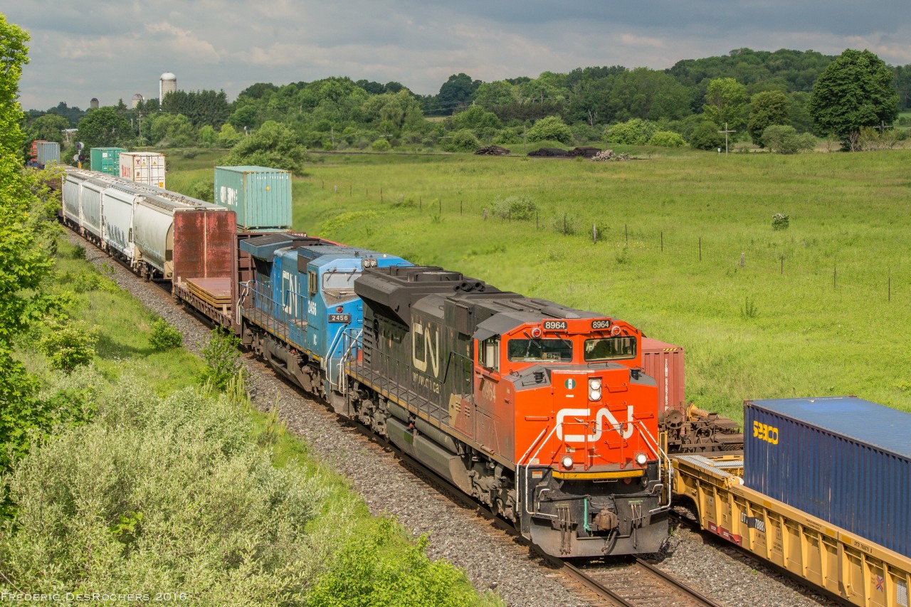 During a small break in the clouds, some morning light bears down on 376 as it passes CN 107 through Newtonville.

107 has a a pair of ACes for power - 8102 & 8101

376 - 8964, IC 2456 & DP 8000