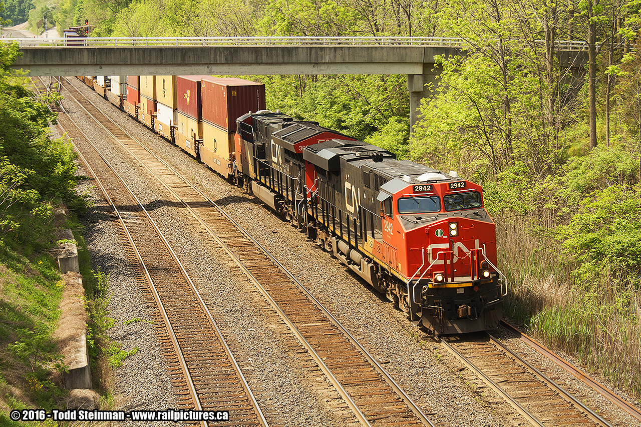 A different take on Bayview...this shot is looking back from the Plains Road overpass to the pedestrian bridge commonly used by railfans. My initial intent of photographing from the overpass was to try and do a Time Machine shot to one of Arnold Mooney's shots from years before, using the east side of the bridge. However, my time was slightly constrained to get one more train, and I captured this freight.

CN 2942 and 3023 lead this eastbound intermodal train off of the Niagara Escarpment via the Dundas Sub., and rolling nicely along through Bayview onward to Vaughan. 

PS - anyone know what the white plastic units are on top of 2942's cab? I am assuming a satellite?