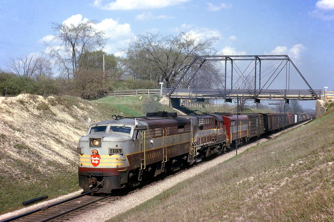Canadian Pacific FA2 4051 passes under London's Sarnia Road bridge in May of 1964, leading a freight with an RS10 and FB1 trailing under the tell-tales. The Sarnia Road bridge was a single lane  structure that had sharp turns leading up to it, and was major bottle neck. It was built in the 1880s crossing CP's Windsor Sub at Mile 3.0 in the west end of London, and was replaced by a modern concrete bridge in 2011.