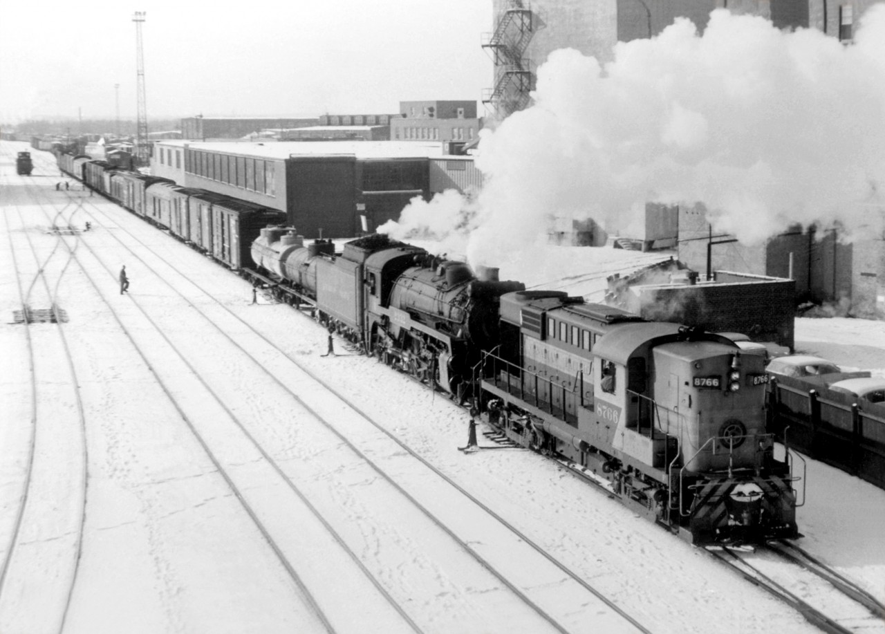 Steam-diesel transition era doubleheader: Canadian Pacific RS18 8766, about a year old at the time, doubleheads with G3 Pacific 2332, backing their train into Lambton Yard past the elevators of Maple Leaf Milling in West Toronto ("The Junction"). The southbound train had just come off CP's northern gateway into town, the MacTier Sub, pulled east onto the North Toronto Sub at Osler, and backed west across the diamonds into the yard.

These kind of movements were common at West Toronto, until a connecting track at the north-west quadrant of the diamonds was built, allowing trains coming off the MacTier Sub bound for Lambton and West Toronto yards a more direct route.