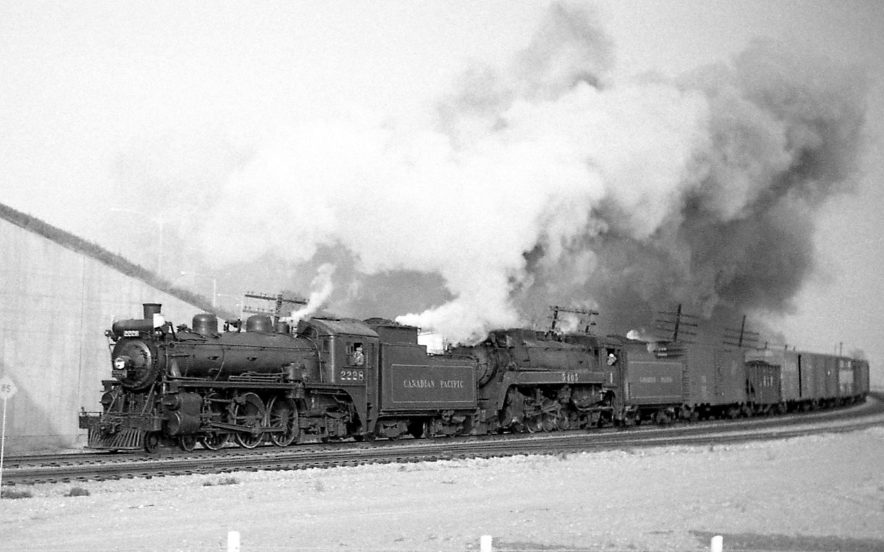 A westbound Canadian Pacific freight passes through Cooksville, just about to pass under the Highway 5 (Dundas Street East) overpass west of the station on October 19th 1959 at 4:30pm. P2g-class Mikado 5405 is in charge of the train, assisted by G1 2228 coupled on the front.