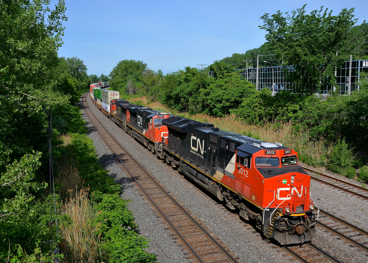 3 GE models at the head end, a fourth mid-train. CN 120 is eastbound on the Montreal Sub with 4 GE units, all different models. Up front is ET44AC CN 3012, ES44DC CN 2230, Dash9-44CW CN 2663, with ES44AC CN 2887 mid-train. This long train bound for Halifax is 624 axles long.