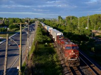 <b>Under storm clouds.</b> CP 8719 & CP 9710 lead CP 133 through Pointe-Claire with a train of piggybacks in tow. Although it is sunny, quite a bit of storm clouds are in the distance.