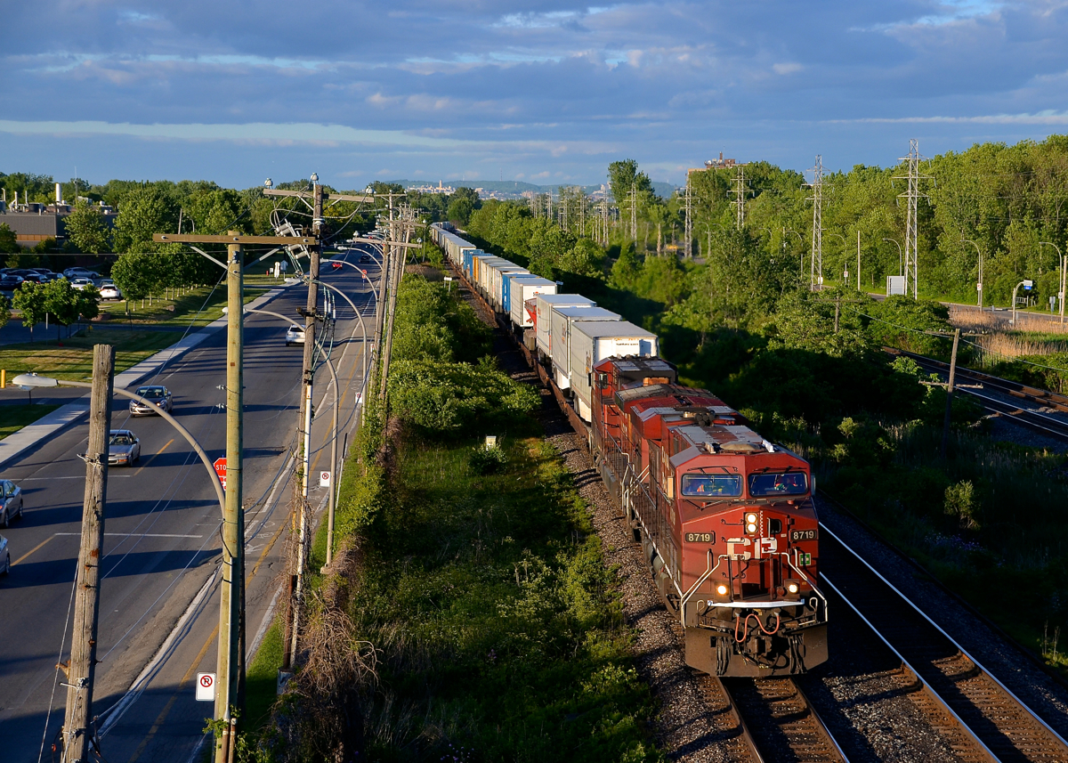 Under storm clouds. CP 8719 & CP 9710 lead CP 133 through Pointe-Claire with a train of piggybacks in tow. Although it is sunny, quite a bit of storm clouds are in the distance.