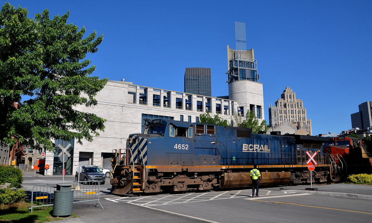 BC Rail leader over a flagged crossing. BCOL 4652 slowly leads CN 149 over a crossing which is being flagged on either side by a Port of Montreal employee on a sunny morning.
