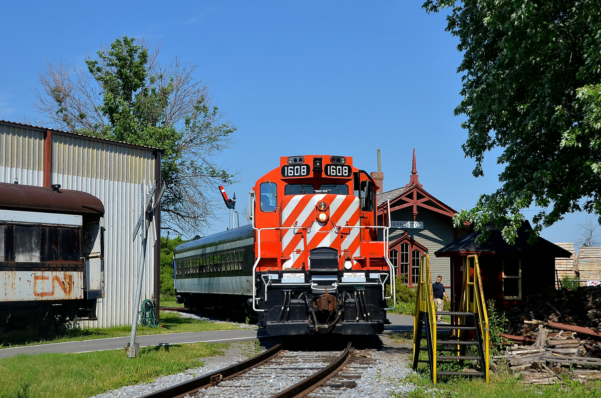 Stopped in front of Barrington Station. Exporail's Sunday-only excursion train is seen in front of Barrington station after its last run of the day. GP9 CP 1608 leads passenger car CN 5064 and at left is small portion of narrow gauge car CN 760 (used in Newfoundland); both of the passenger cars were built by Canadian Car & Foundry in Montreal. At right is a staircase that is used to load the wood at right into the John Molson steam engine.