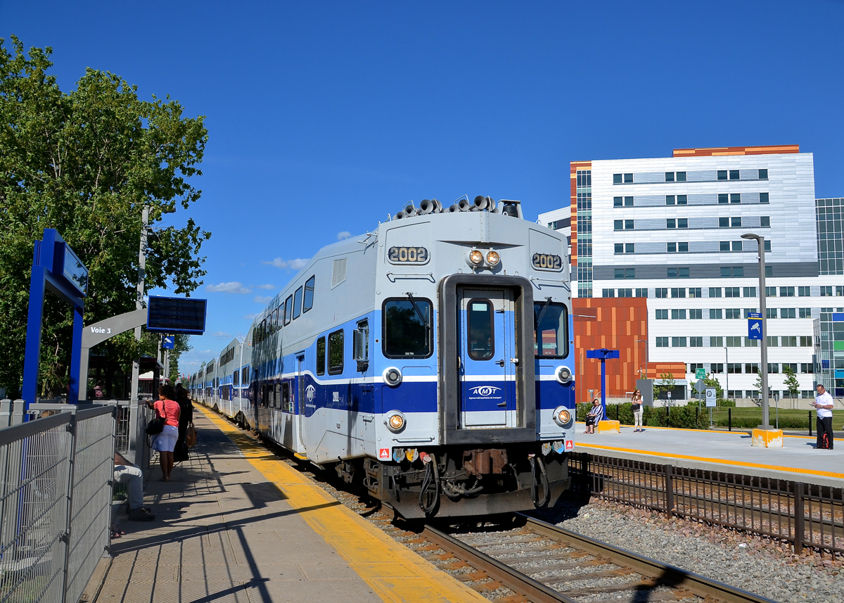 Past the 'superhospital'. Cab car AMT 2002 leads AMT 187 (bound for Saint-Jérôme) towards its first stop at Vendôme Station. To the right of the train is the recently opened McGill University Health Centre, dubbed the superhospital locally. It was built on the site of CP's Glen Yard.