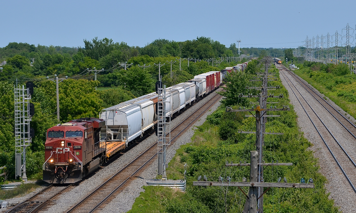 CP 119 wins another race. Three weeks back I shot CP 119 on the CP Vaudreuil sub with a lead over CN 327 on the parallel CN Kingston sub in Pointe-Claire. Here, a bit further west in Sainte-Anne-de-Bellevue, CP 119 is winning another race, with CN 327 off in the distance. CP 119 is doing track speed whereas CN 327 is just starting to accelerate after having to hold for three eastbounds and one westbound ahead of it due to a work block. CP 119 has CP 8816 at the head end and CP 8636 mid-train.