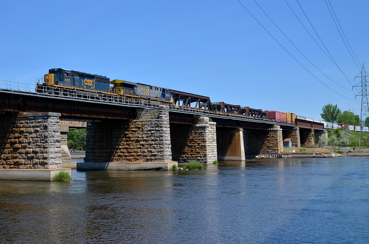 A SpongeBob and a big AC6000CW. 'SpongeBob SquareCab' SD40-3 CSXT 4071 and AC6000CW CSXT 675 lead a short CN 327 (43 cars) over the Ottawa River on a scorching day.