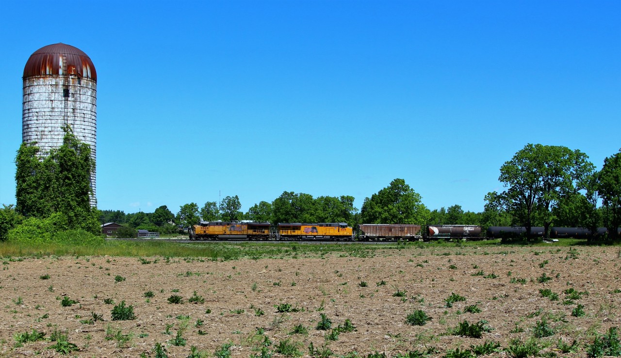 Having not saw much foreign power around lately, this pair of Union Pacifics was a nice surprise. With all the sun angles being bad in the area at this time of day for a west bound, an across the field shot was the only choice. Here we find UP 5509 leading UP 5519 up the Galt sub approaching Victoria Road with a near 7800 foot ethanol train.