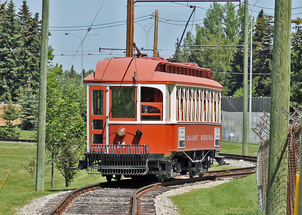 On a beautiful sunny morning Heritage park tram #14 makes its way around the lake and parking lot taking passengers to the Park's main entrance.  The tram comprises a replica body riding on original street car #14 chassis.